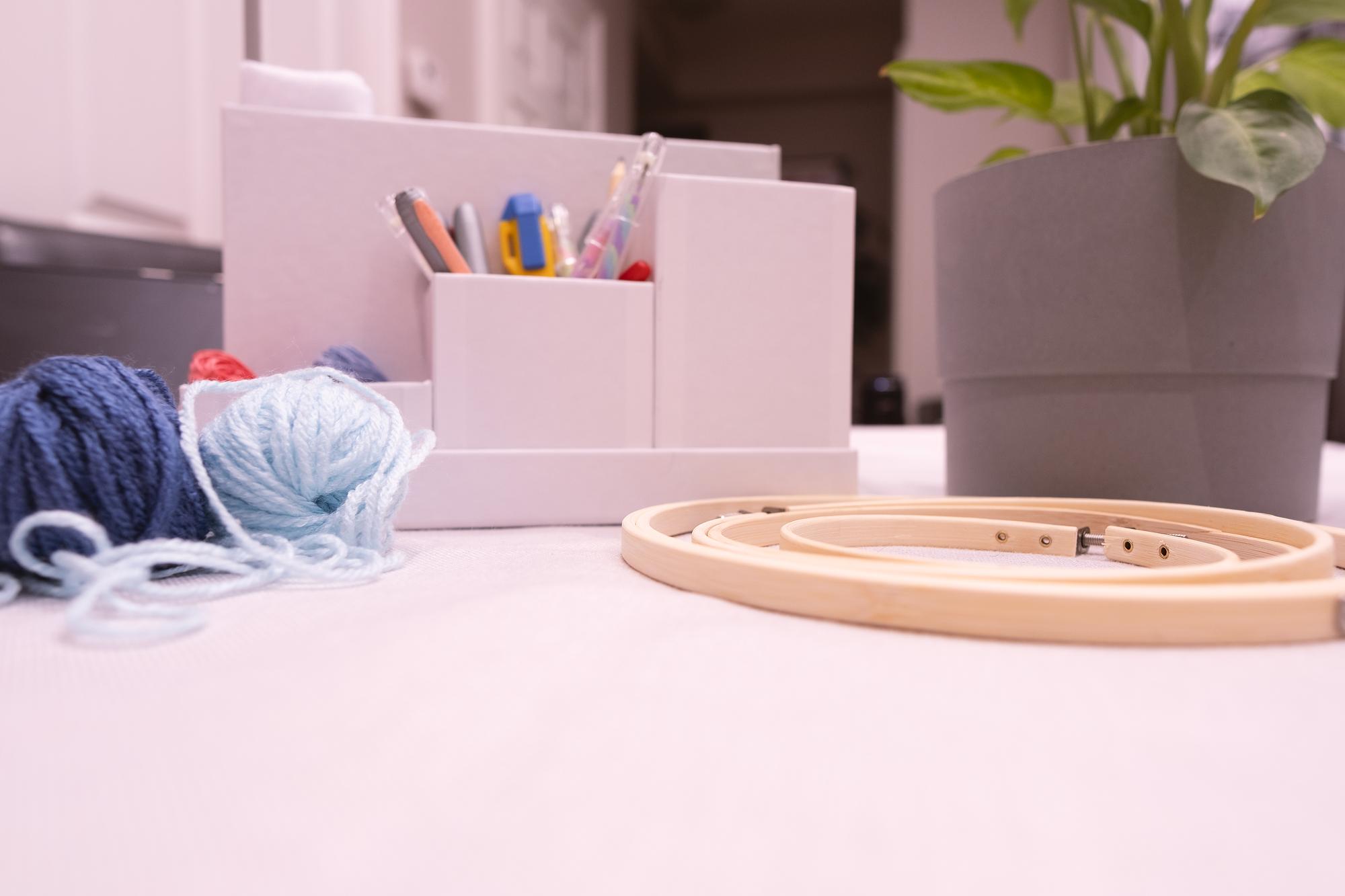 atelier workspace with threads and hoops on pastel table